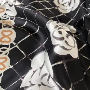 Détail en gros plan d'un foulard en soie luxueux noir et blanc avec un motif élégant de camélia.