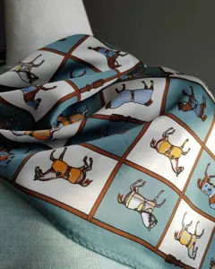 Pañuelo de seda verde menta con estampado de caballos y cinturones, accesorio versátil.