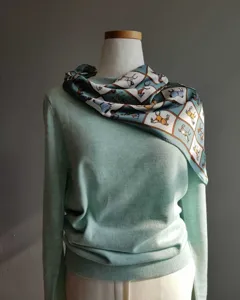 Exquisito jersey verde menta combinado con un elegante pañuelo de seda con motivo de caballos.
