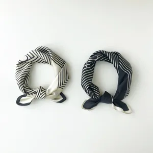 Detail view of monochrome geometric silk neck scarf, elegant striped print and minimalist design.