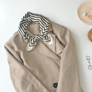 Elegant black and white geometric silk square scarf paired with a stylish khaki blazer for women.