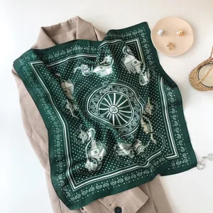 Detailed view of a dark green silk scarf featuring classic carriage and paisley patterns.