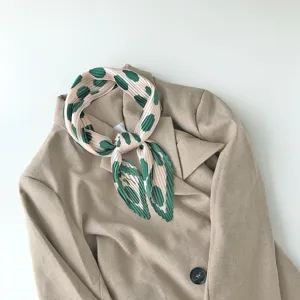 Detailed view of a pleated printed square scarf featuring chic green polka dots on pink fabric.