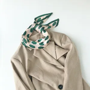 Elegant pleated neckerchief with green dot pattern draped on chic blazer for stylish women wear.