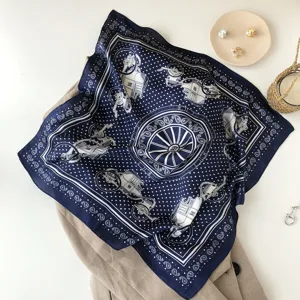 Detailed view of the dark blue silk scarf featuring elegant carriage print and classic polka dots.