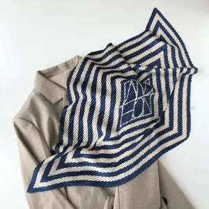 Close-up detail of pleated geometric square scarf draped elegantly over a stylish outerwear.