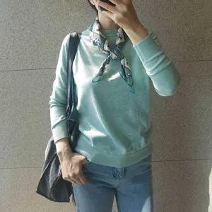 Elegante jersey verde menta para mujer combinado con pañuelo de seda con estampado.