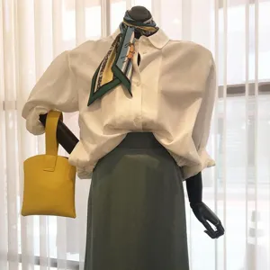 Dames modekleding set met wit shirt, groene rok en chique zijden sjaal accessoires.