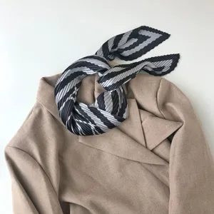 Close up of pleated black and white striped small neck scarf styled on a blazer.