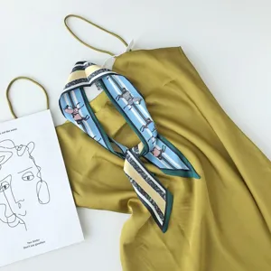 Detailopname van een zijden sjaal met paardenprint en een olijfgroene camisole top.