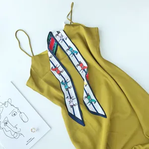 Close-up detail van een gele slipdress gestyled met een paardenprint smalle zijden sjaal.