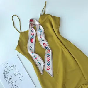 Elegante gele jurk met spaghettibandjes en stijlvolle geometrische zijden sjaal voor dames.