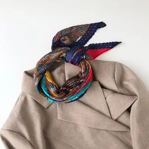 Detailed view of the colorful printed pleated silk scarf featuring geometric stripe and dot patterns.