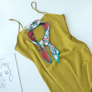 Elegante gele slipdress gecombineerd met een chique smalle zijden sjaal met print.