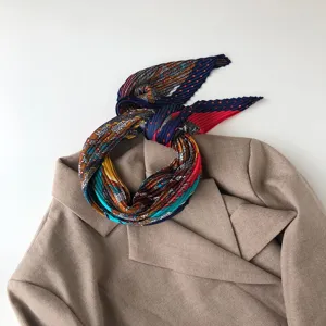 Detailed view of a pleated geometric printed silk scarf elegantly draped on a chic tweed jacket.