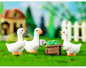 Vue détaillée de figurines de canards en résine miniatures dans un jardin, décoration de bureau.