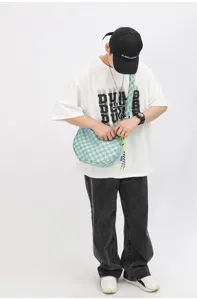 Λεπτομερής άποψη της μοντένας ανοιχτοπράσινης καρό τσάντας χιαστί με μοναδική υφή.