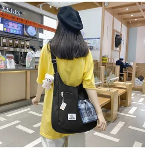 Sac bandoulière noir en toile style coréen avec poche à cordon écossaise et pendentif.