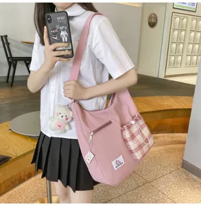 Sac bandoulière en toile rose avec poche à carreaux et pendentif ours pour le quotidien.