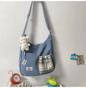 Vue détaillée d'un sac bandoulière en toile bleue avec charmant peluche et poche.