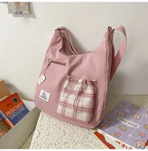 Détail de sac bandoulière en toile rose, jolie poche cordon à carreaux et style hobo chic.