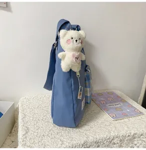 Sac bandoulière en toile bleue style coréen avec pendentif ours en peluche et poche à carreaux.
