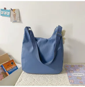 Détail de sac bandoulière bleu décontracté montrant tissu doux, sangle réglable et pendentif d'ours.