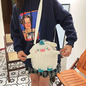 Nahaufnahme einer niedlichen flauschigen weißen Monster Umhängetasche mit Stickerei Details.
