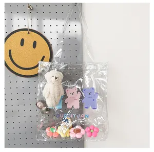 Transparente PVC-Tragetasche mit niedlichen Cartoon-Bärenanhängern und bunten Blumenanhängern.