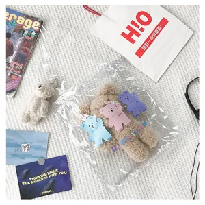 Nahaufnahme der transparenten PVC-Tasche mit flauschigem Bären und bunten Bären-Anhängern.