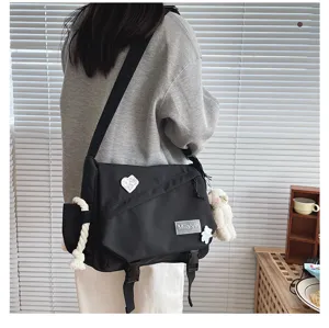 Casual black messenger bag for students, large capacity crossbody bag with bear charm and pin.