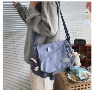 Casual messenger shoulder bag detail view showing canvas material, flap design and plush charm.