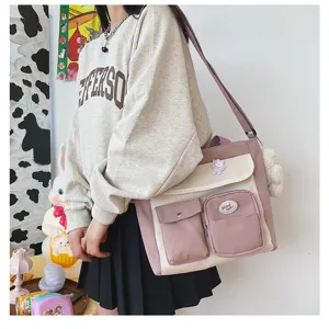 Canvas messenger bag multi-pocket detail view with cute plush pendant and patch decor.