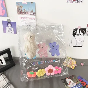 Detailansicht der durchsichtigen Handtasche mit Plüschbärchen Anhänger und bunten Blumen.