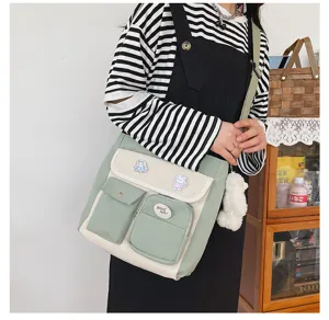 Detailed view of the canvas messenger bag with multi pockets, cute badges and plush charm.