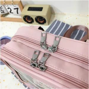 Primer plano de las cremalleras dobles de la mochila de cuero PU rosa y bolsillo.