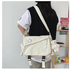 Casual canvas messenger bag detail view, minimalist style with cute bear pendant.