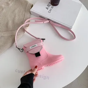 Détail de sac bandoulière forme botte de pluie rose, design de nouveauté créatif avec sangle.