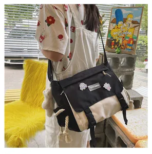 Casual canvas color-block messenger bag detail view with stylish rope and badge accents.