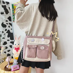 Detailed lifestyle view of a pink and beige canvas crossbody bag with cute badges and pendant.