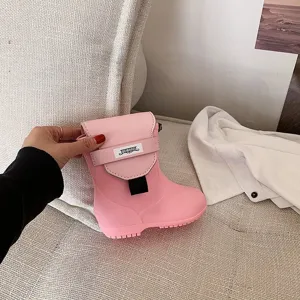 Vue détaillée d'un sac bandoulière créatif en forme de botte de pluie rose avec étiquette.