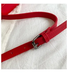Primo piano del dettaglio di una tracolla per borsa in pelle PU rossa con fibbia in metallo.