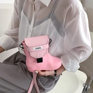 Gros plan sur les détails du sac à bandoulière créatif en forme de botte rose avec sangle.
