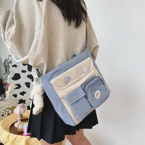 Canvas crossbody bag with multi-pockets and cute badge detail, perfect for student daily use.