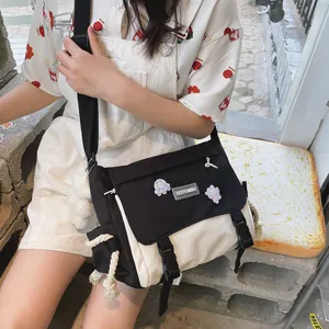 Canvas messenger bag detail view, black and white color block design, casual student style.
