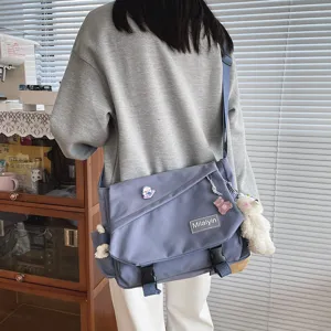 Detail view of casual canvas messenger bag with cute bear pendant and spacious design.