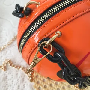 Close-up detail of the orange pumpkin novelty handbag featuring gold hardware and acrylic chain.
