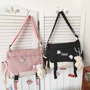 Canvas messenger bag detail showing cute plush bear pendant and colorful kawaii anime pins.
