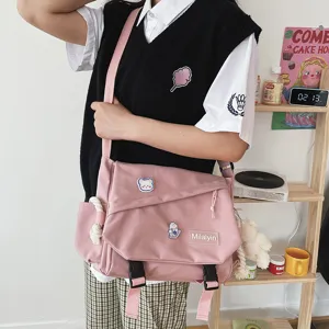 Detailed view of the pink canvas messenger bag with cute badges and large capacity design.
