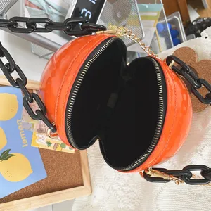 Close-up detail of the stylish orange round crossbody bag with chunky black acrylic chain.